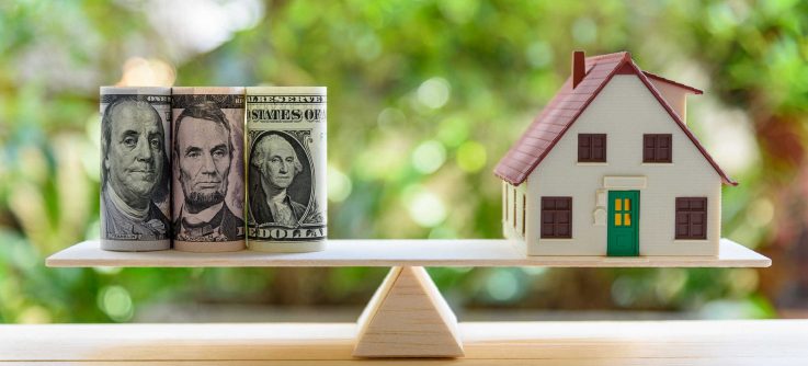 Home loan / reverse mortgage or transforming assets into cash concept : House model, US dollar notes on a simple balance scale, depicts a homeowner or a borrower turns properties / residence into cash