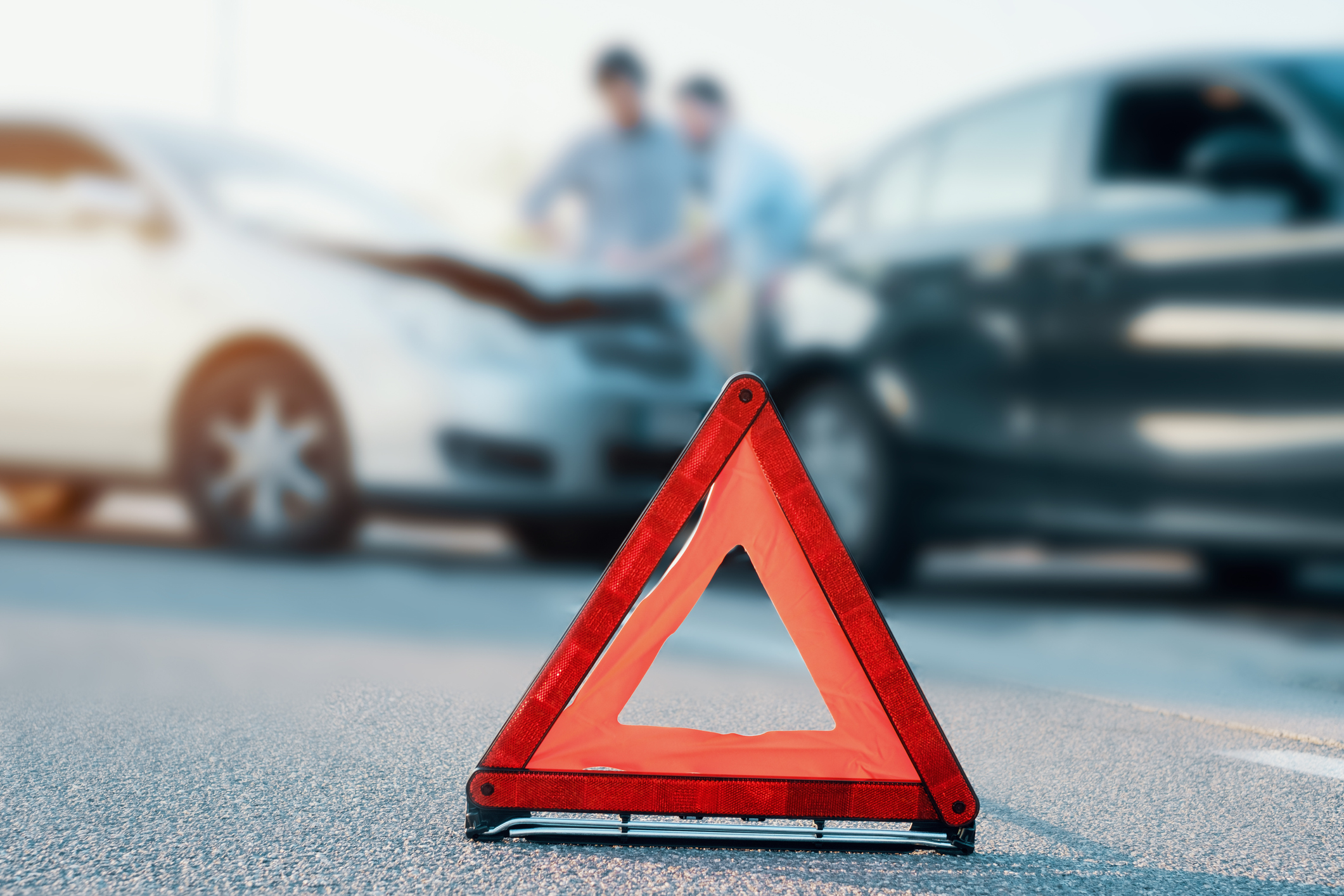 Two men reporting a car crash for the insurance claim,main focus on red triangle