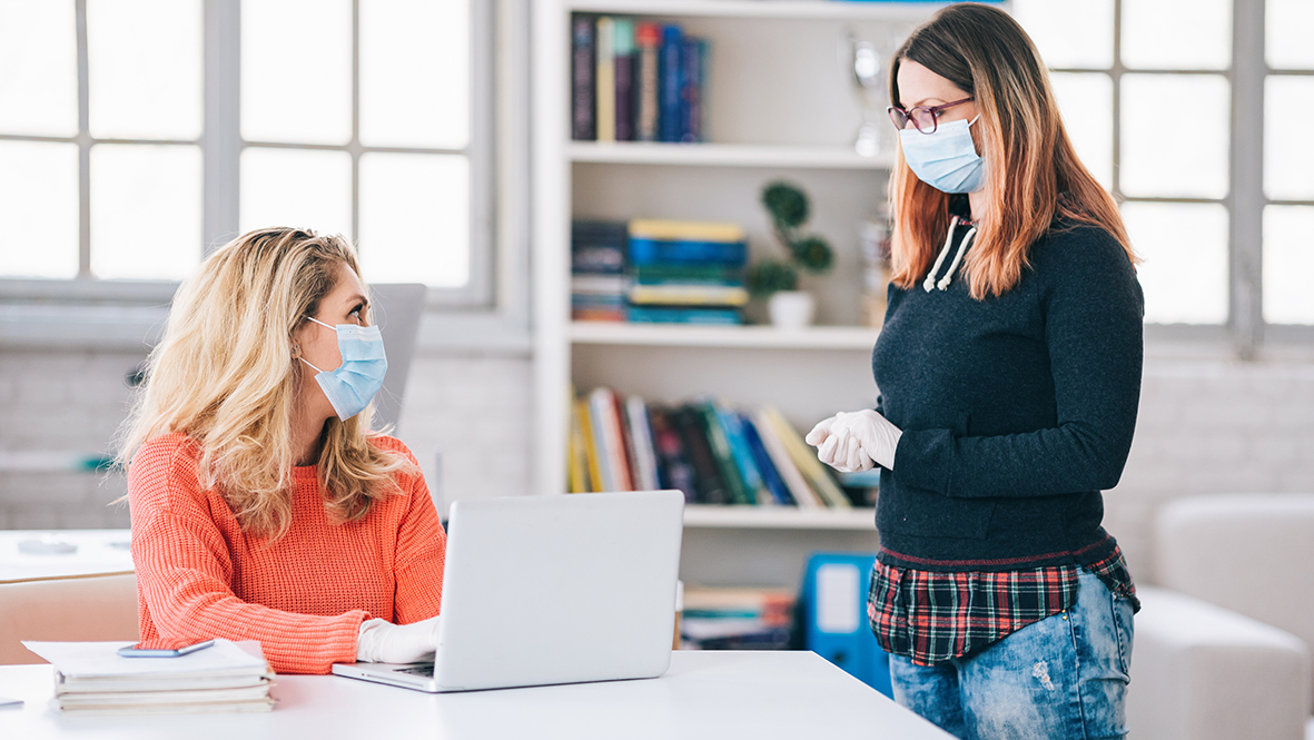 Colleagues in the office working while wearing medical face mask during COVID-19