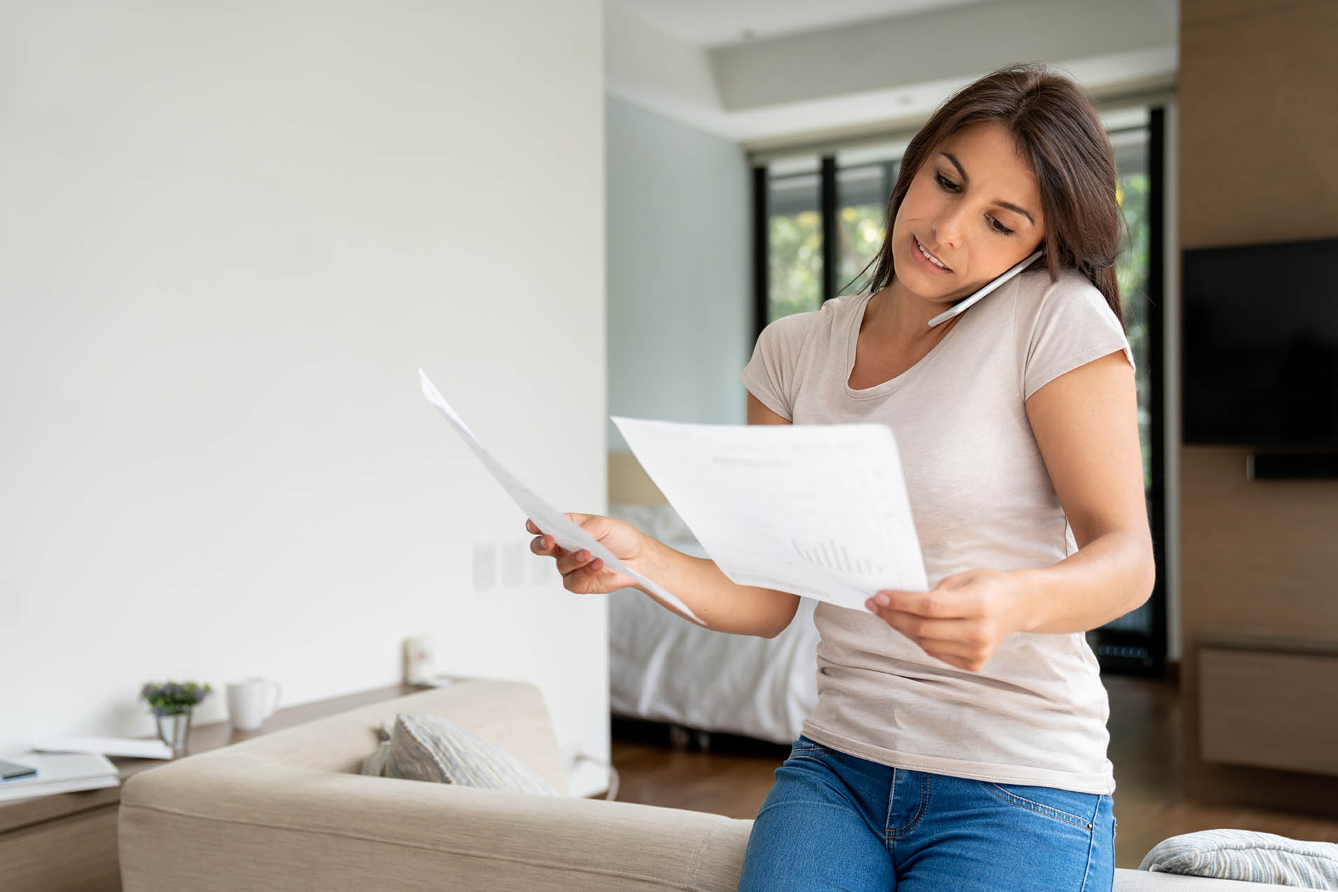 Portrait of a Latin American woman at home talking to customer service about a bill