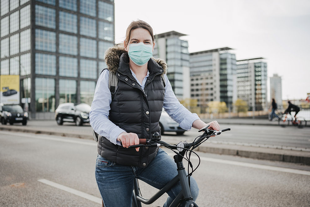 Woman with a protective face-mask riding on a bike in Berlin.