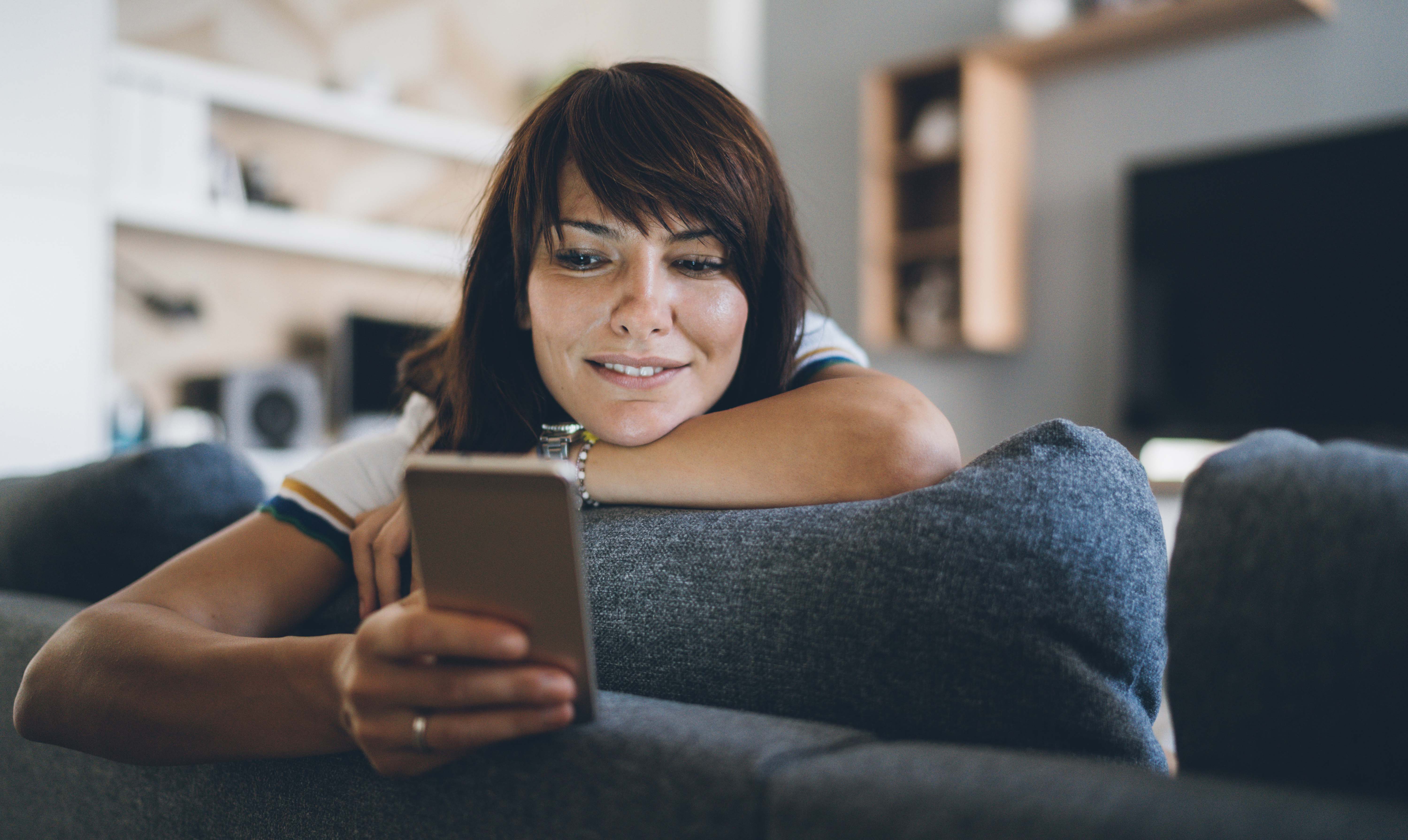 Young bautiful woman texting surfing the net on the sofa at home