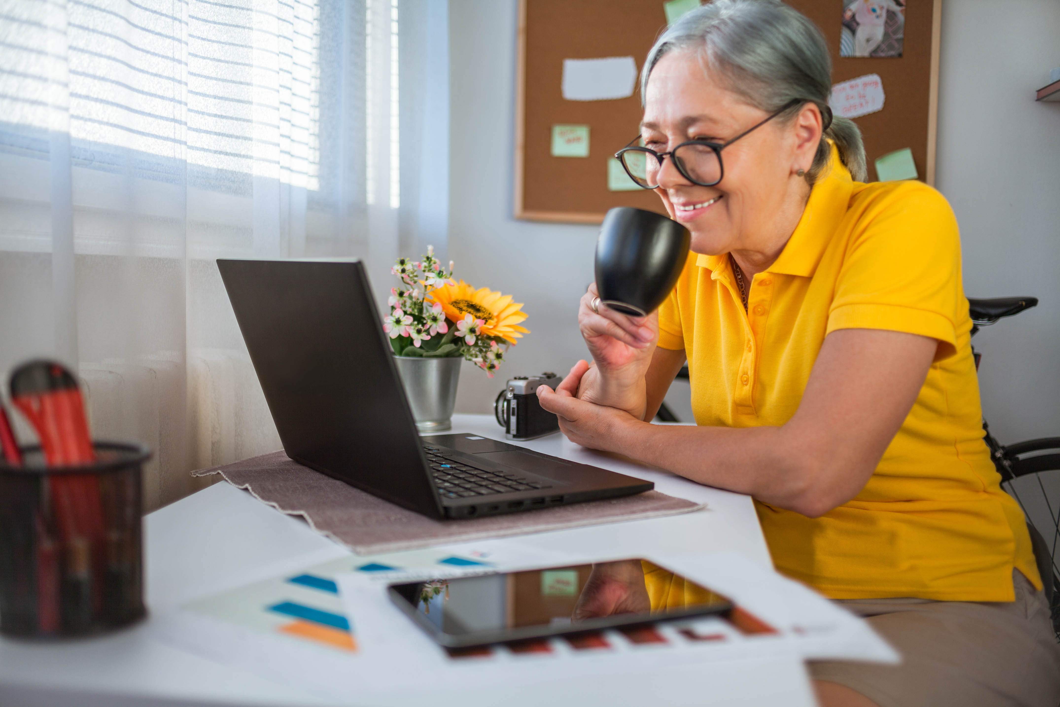 Close up of Senior woman drinking coffee and using laptop during at home