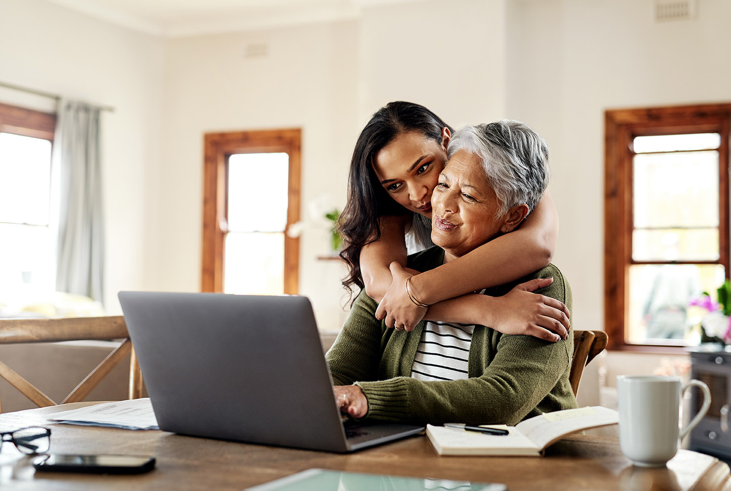 Cropped shot of an attractive young woman hugging her grandmother before helping her with her finances on a laptop