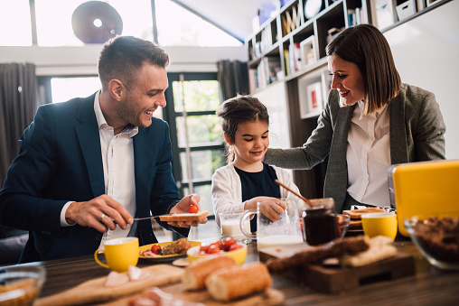 Young couple and their daughter having a breakfast together.