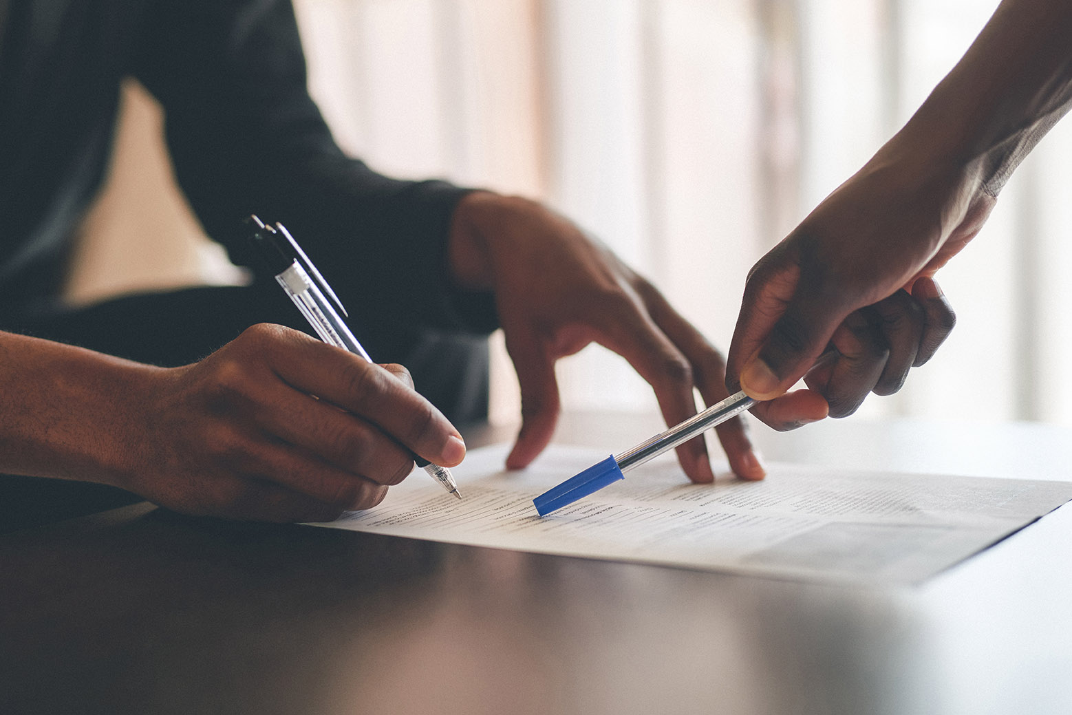 Cropped shot of an unrecognizable man filling a document with the help of a financial advisor at home