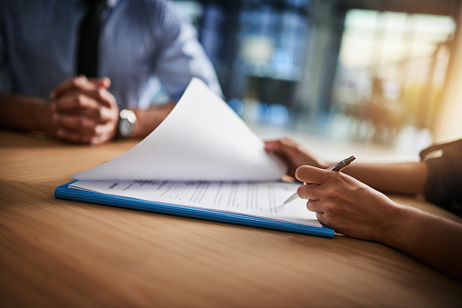 Cropped shot of a man and woman completing paperwork together at a desk