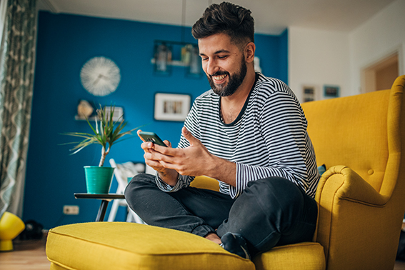 Man sitting home in his armchair and using phone