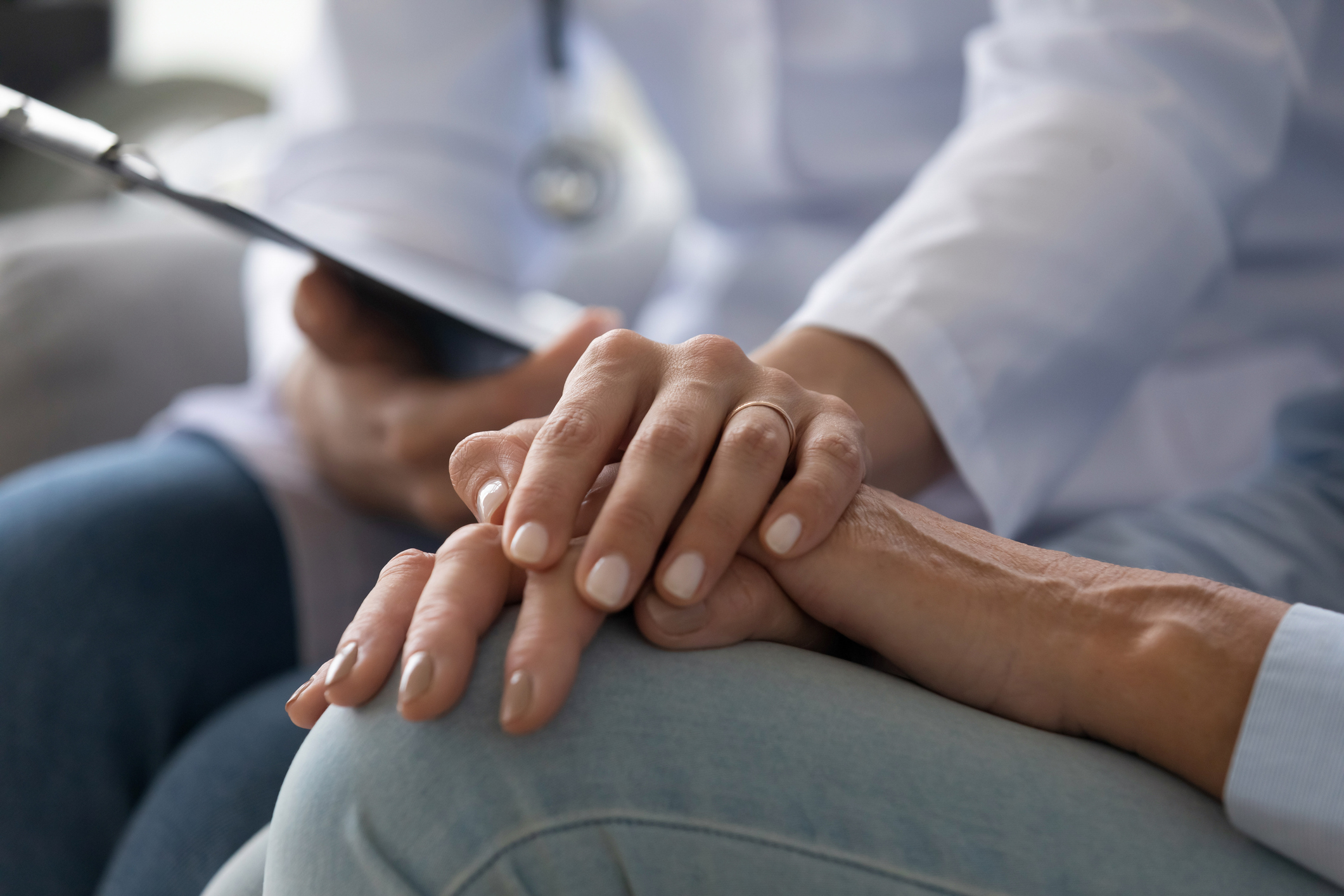 Young woman doctor nurse wear white medical uniform holding hand of senior old female grandmother patient having disease health problem give support help empathy and comfort concept, close up view