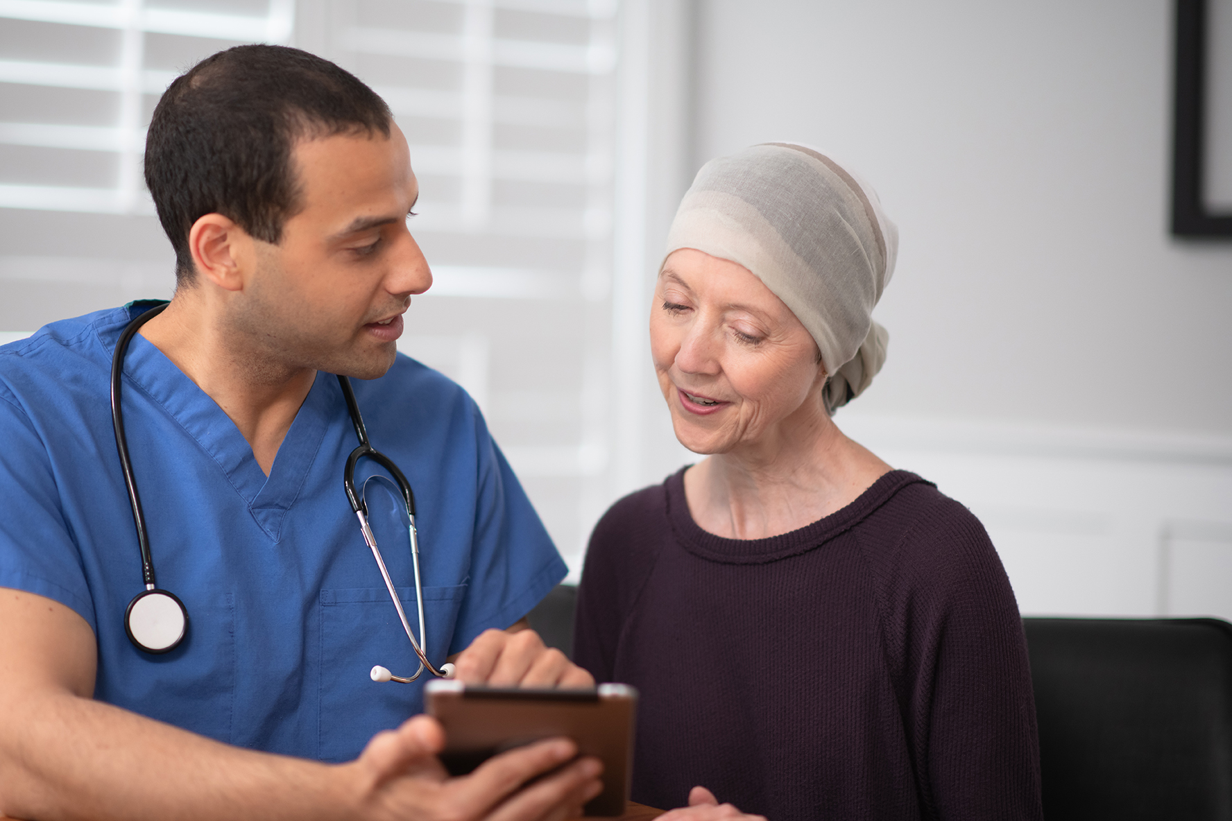 An elderly oncology patient reviews testing results with her mixed race male doctor in his office