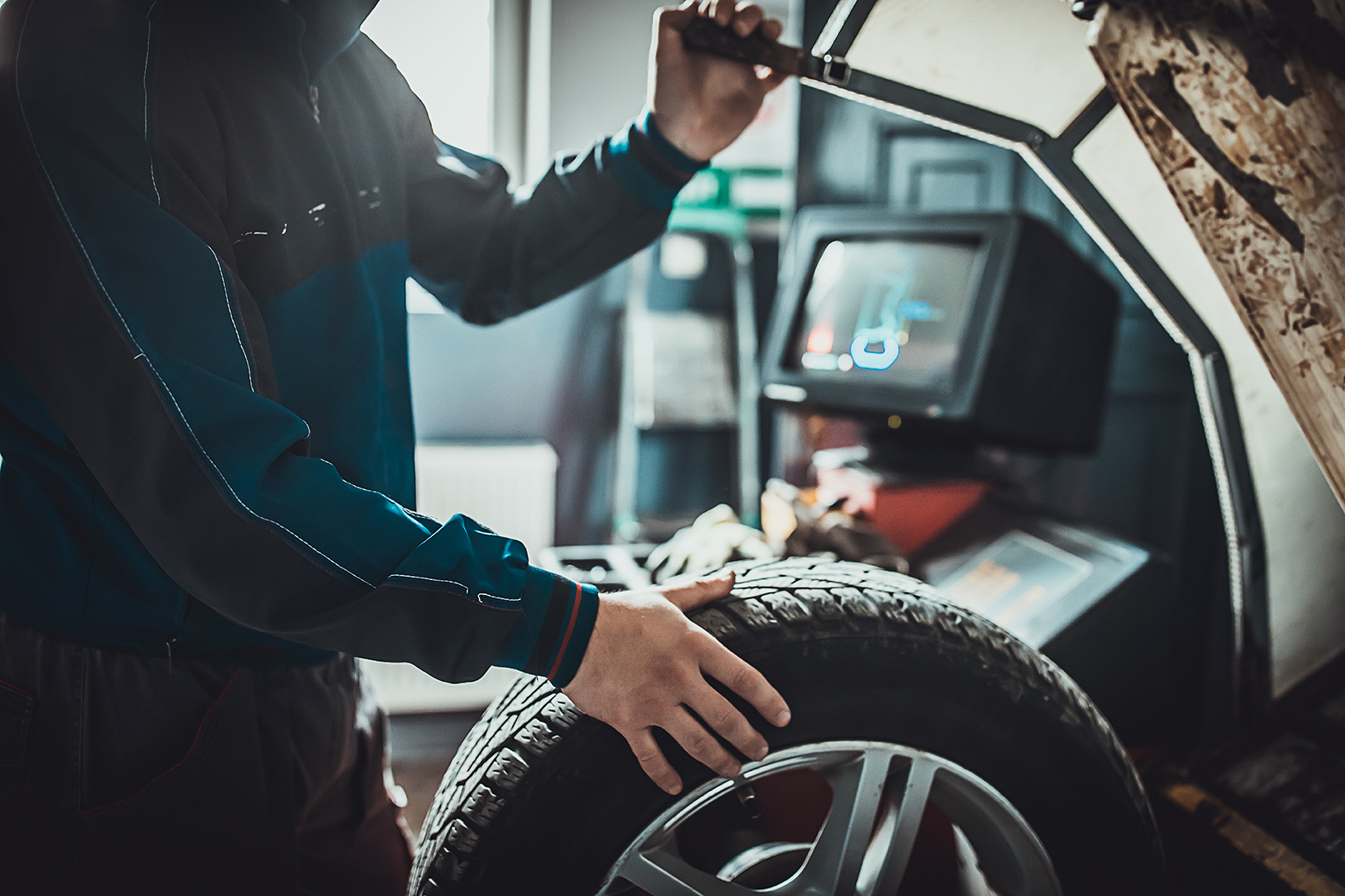 One young mechanic balancing a tire in auto repair shop.