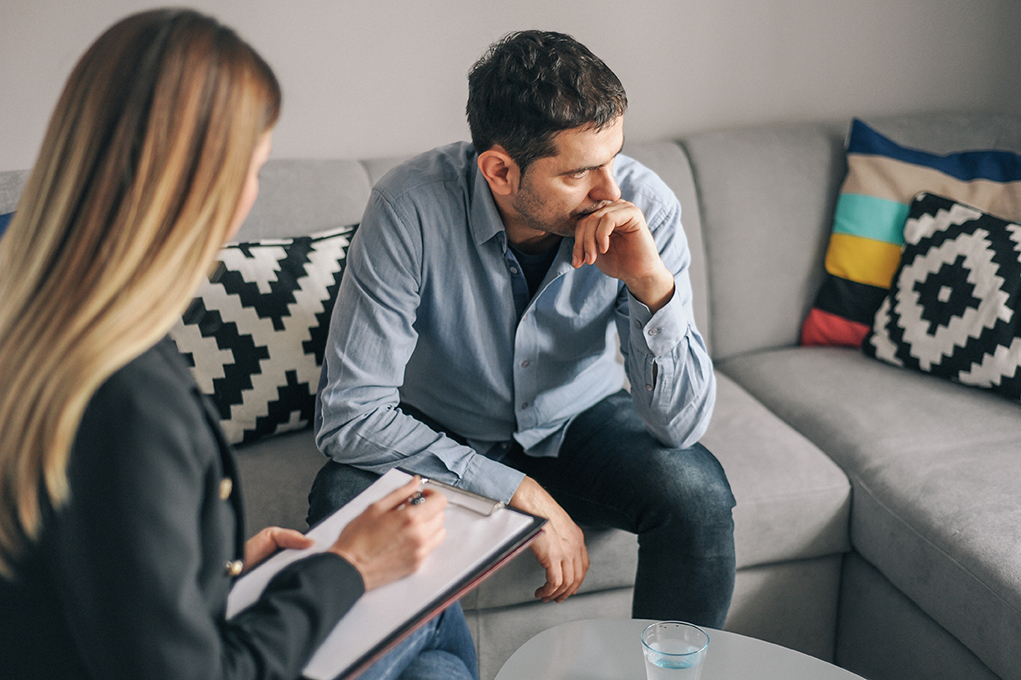 Young man, alcoholic, talking to female therapist about his problems, on  therapy session