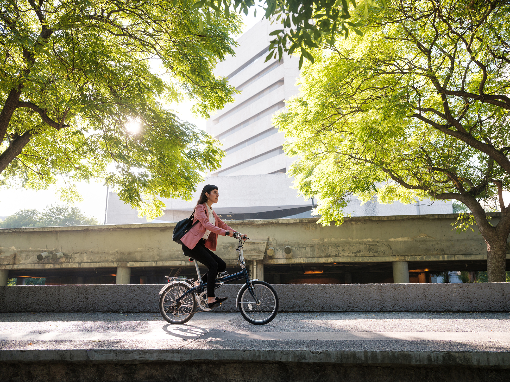 A young mexican woman riding her bike in the city and going to work.