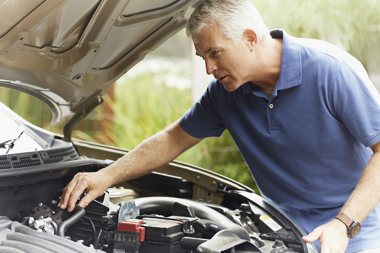 Concentrated mature man fixing his car engine outdoors