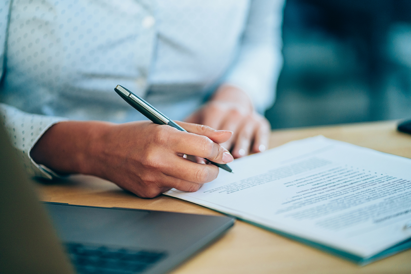 Close-up shot of a businesswoman holding a pen and signing contract.