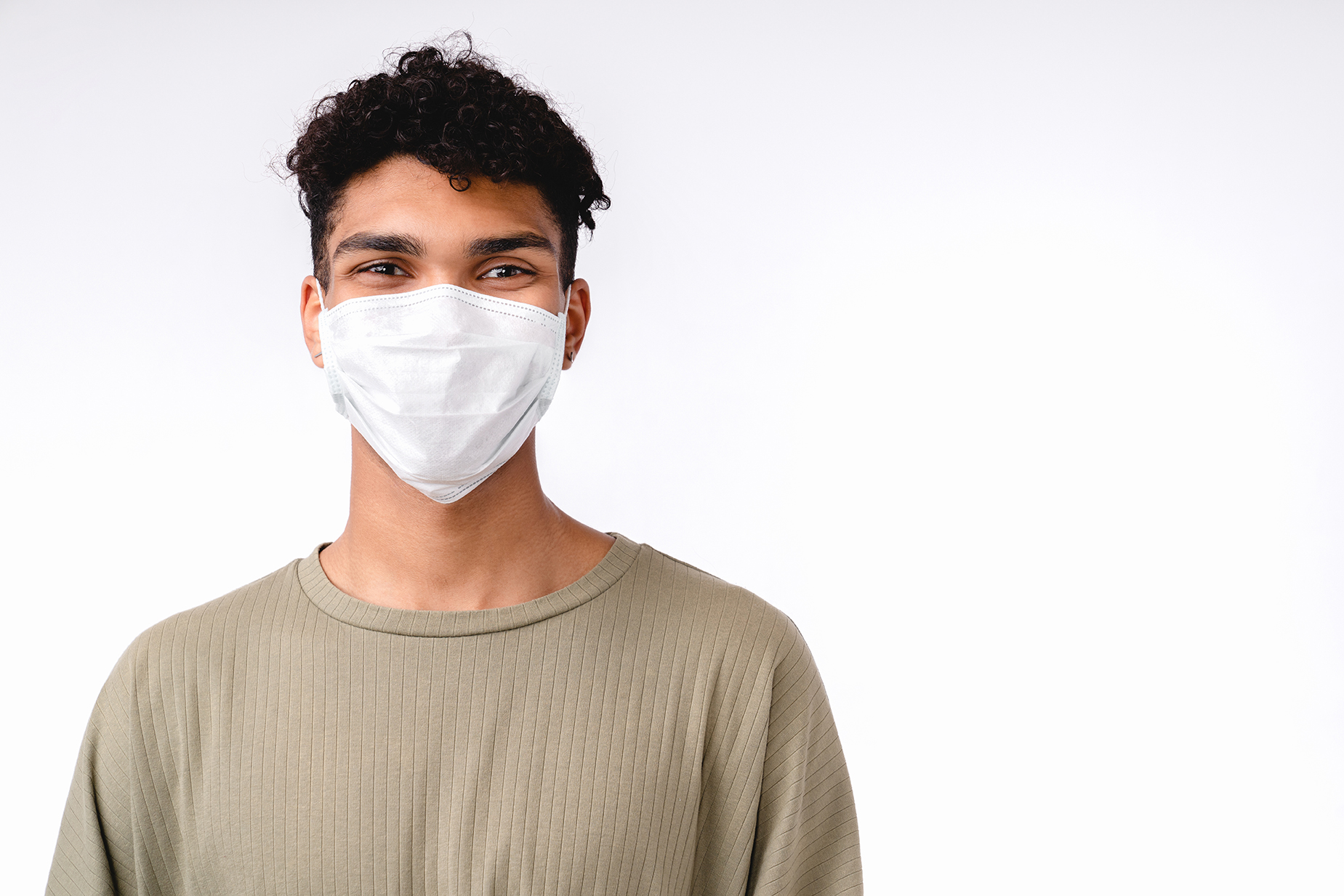 Handsome young mixed-race man wearing medical mask against coronavirus isolated over white background