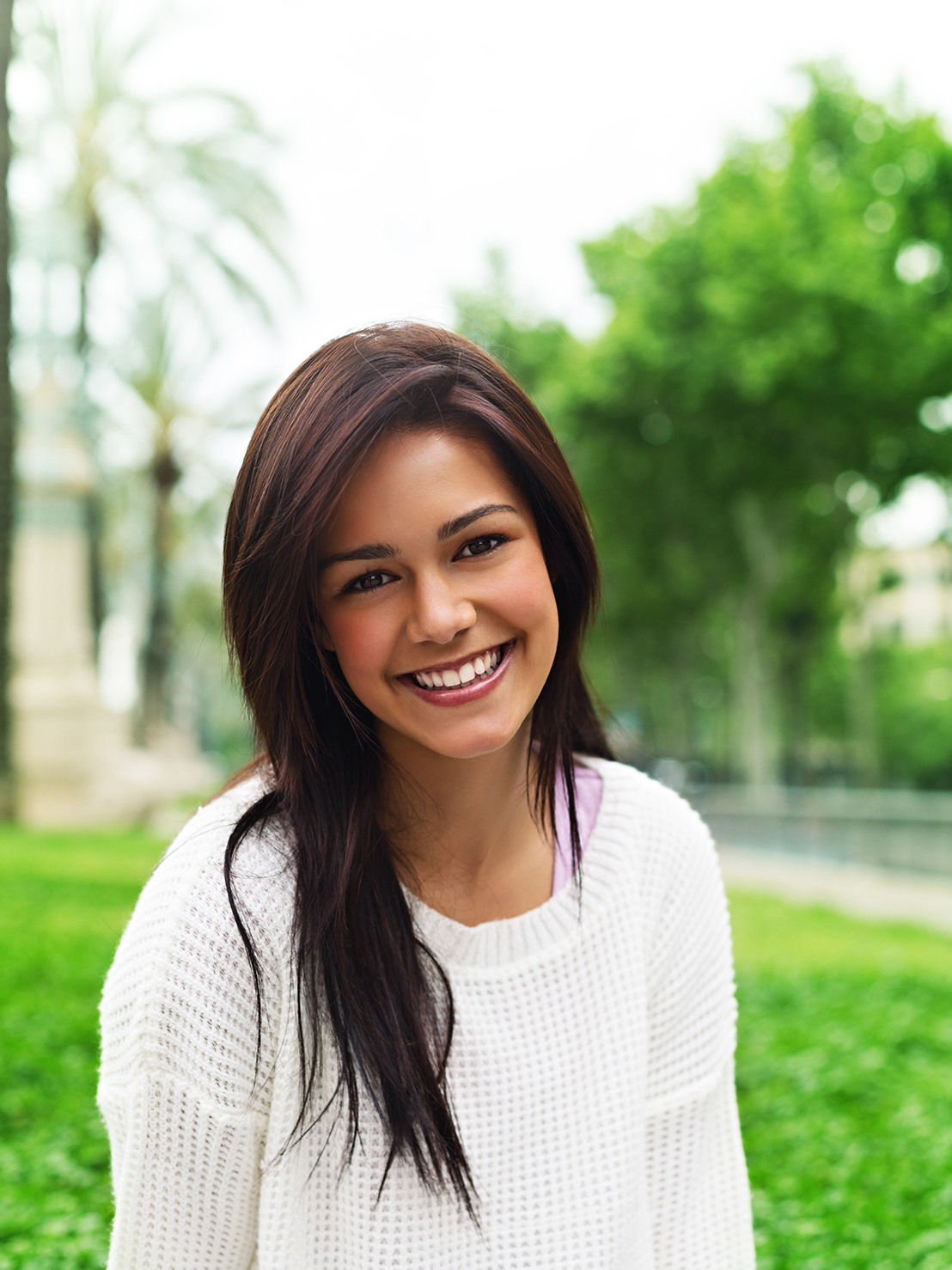 Young woman looking at camera and smiling in a park.