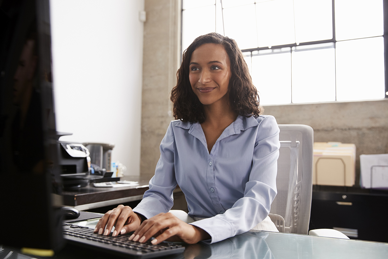 Young mixed race woman using computer at office desk
