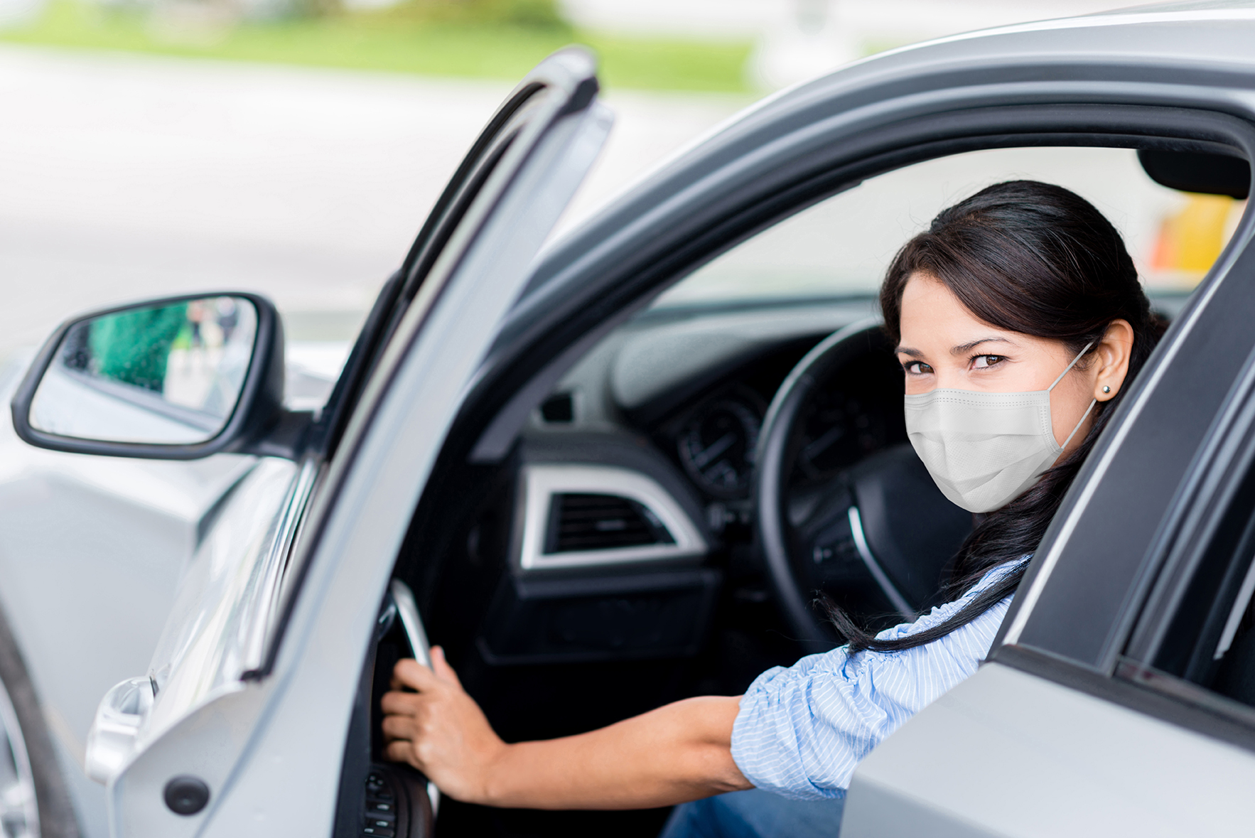 Woman getting out of the car to refuel it and wearing a facemask at the gas station â COVID-19 pandemic concepts