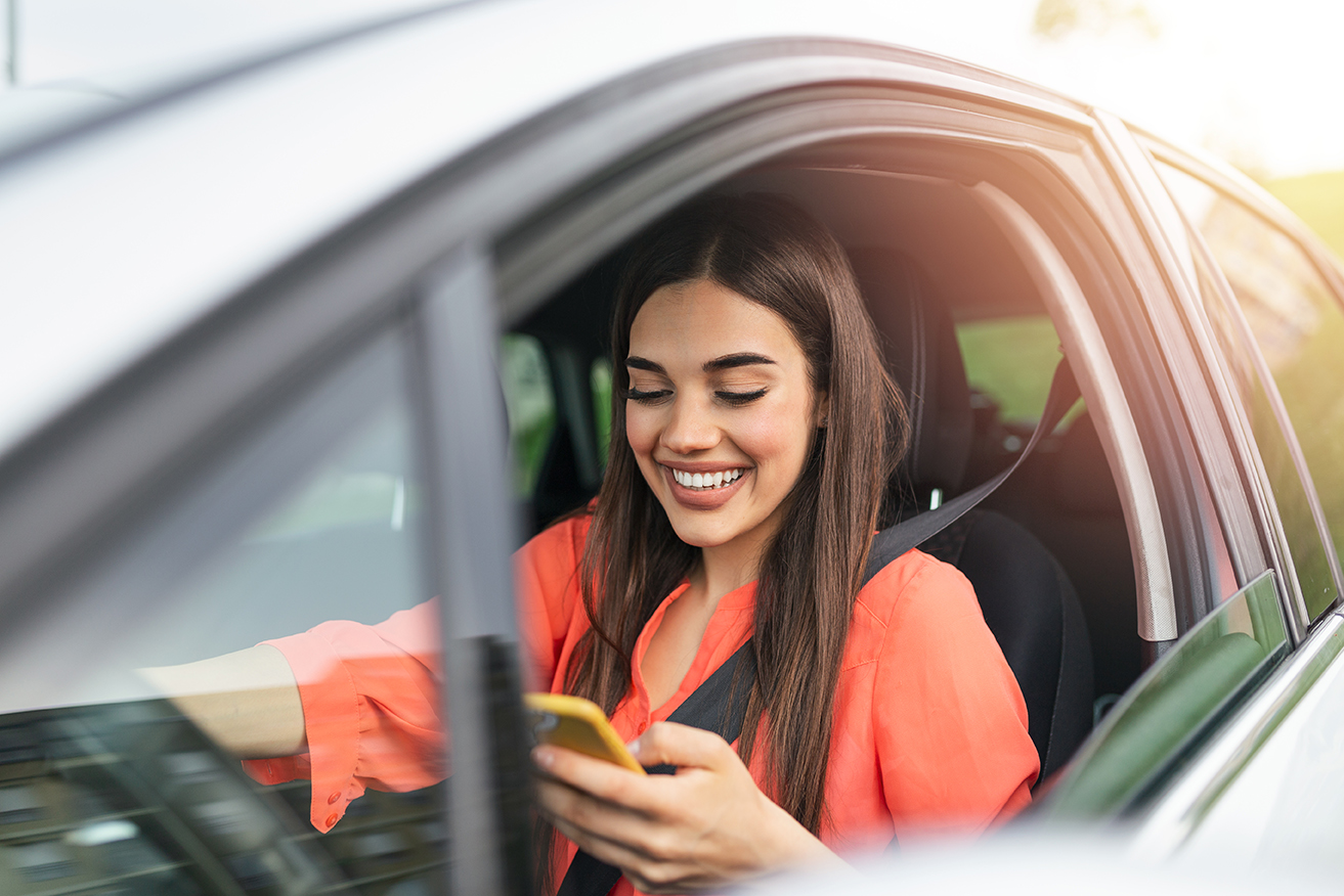 Woman driver using a smart phone in car. Woman driver using a smart phone in car. Leisure, road trip, technology, travel and people concept - Happy woman driving car with smartphone