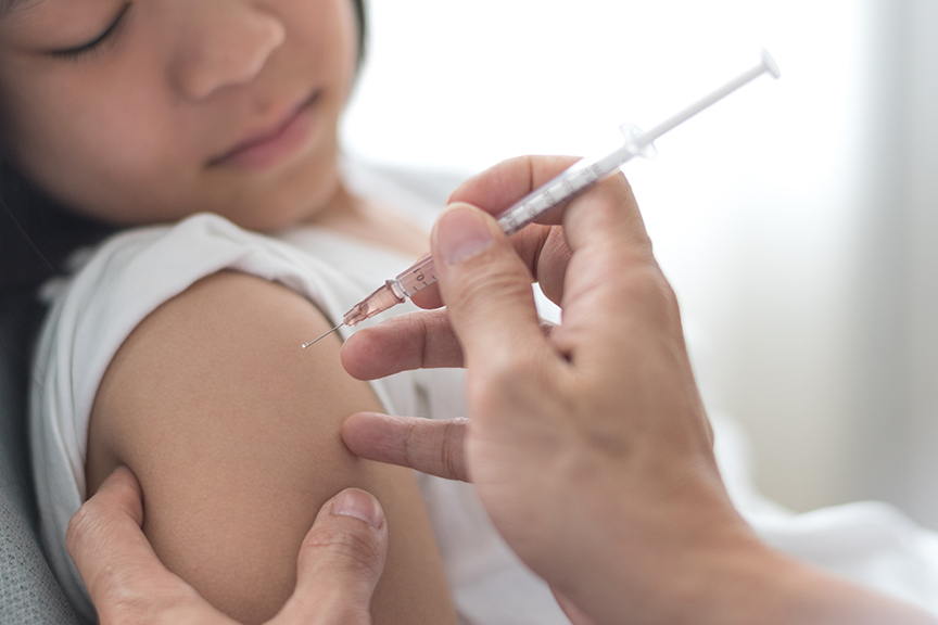 World immunization week and International HPV awareness day concept. Strong happy healthy Asia kid girl smiling getting vaccination for influenza or flu shot or HPV prevention with doctor pediatrician's hand holding medical syringe in hospital