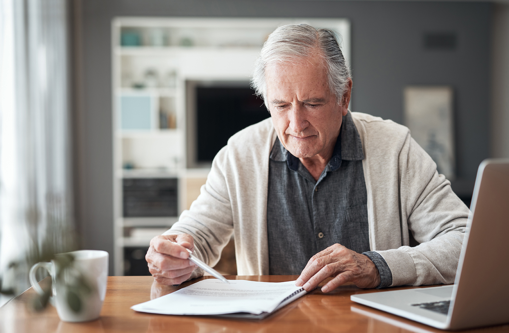 Cropped shot of a senior man sitting alone at home and going through his finances