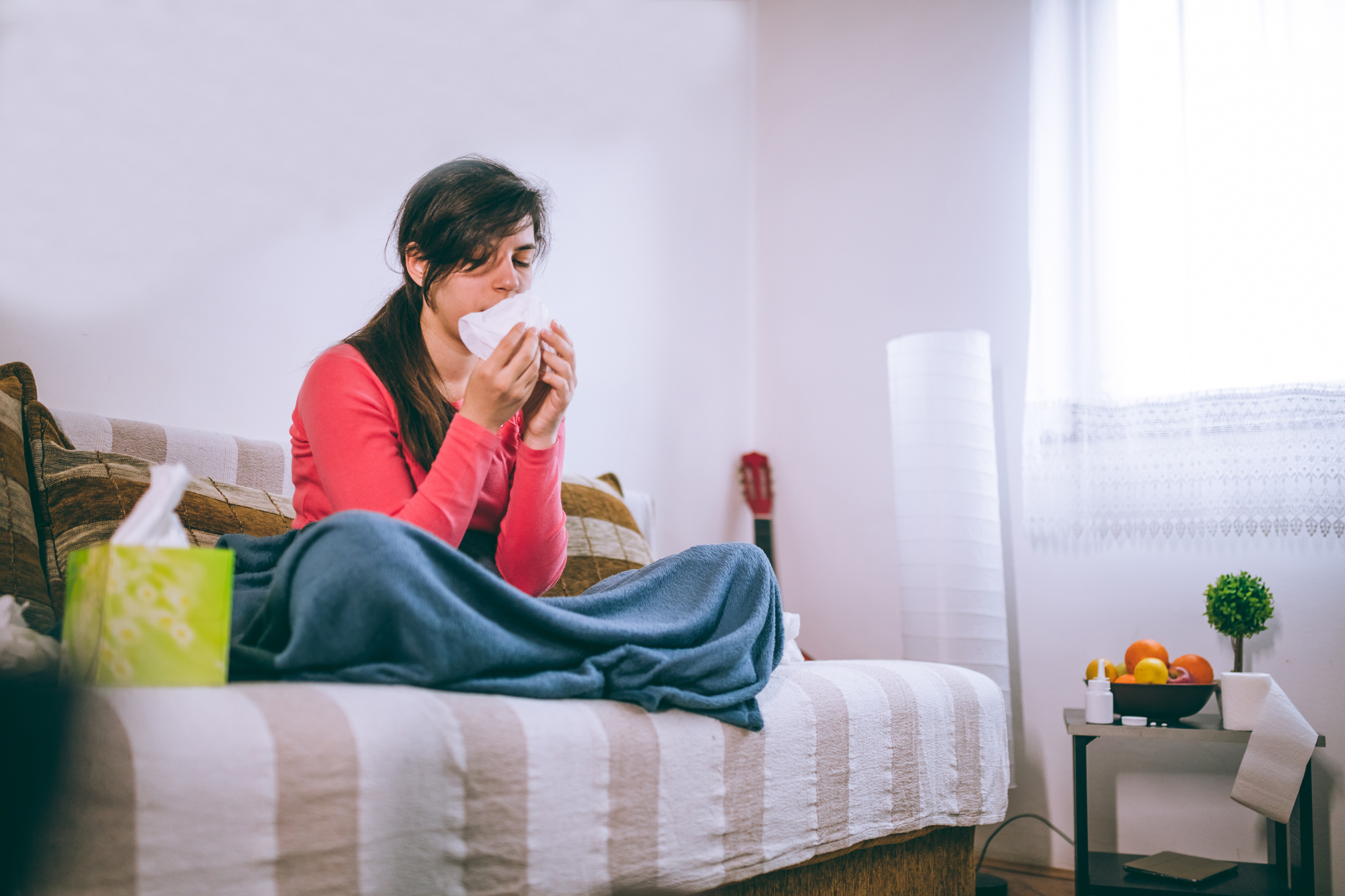 Young woman lying at home struck with a flu or seasonal cold.