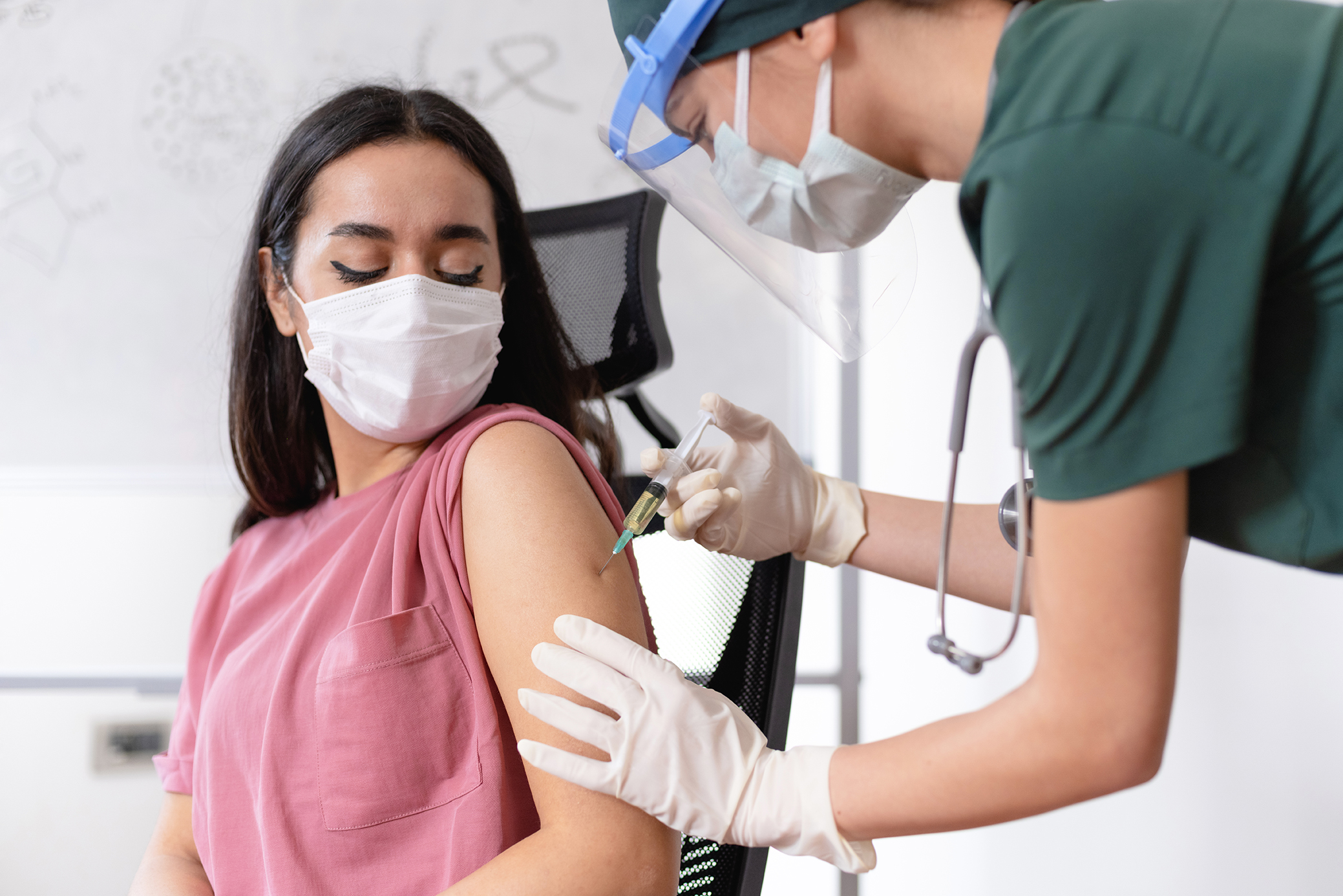 Female Doctor Or Nurse Giving COVID-19 Vaccination Shot To Her Patient At The Clinic