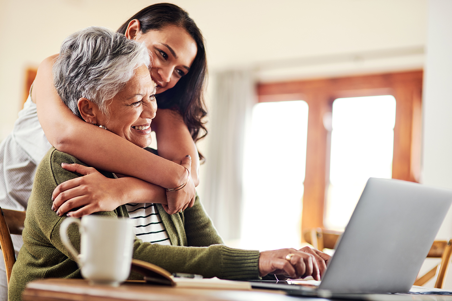 Cropped shot of an attractive young woman hugging her grandmother before helping her with her finances on a laptop