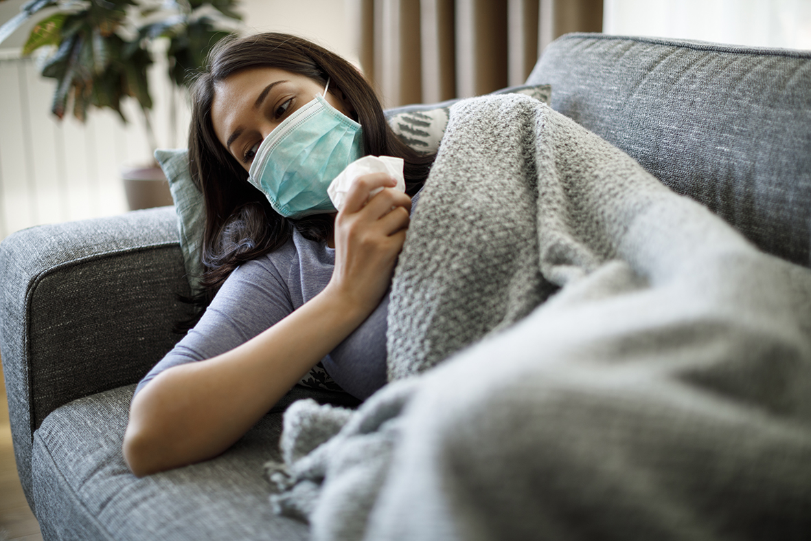 Sick woman with face protective mask lying in bed