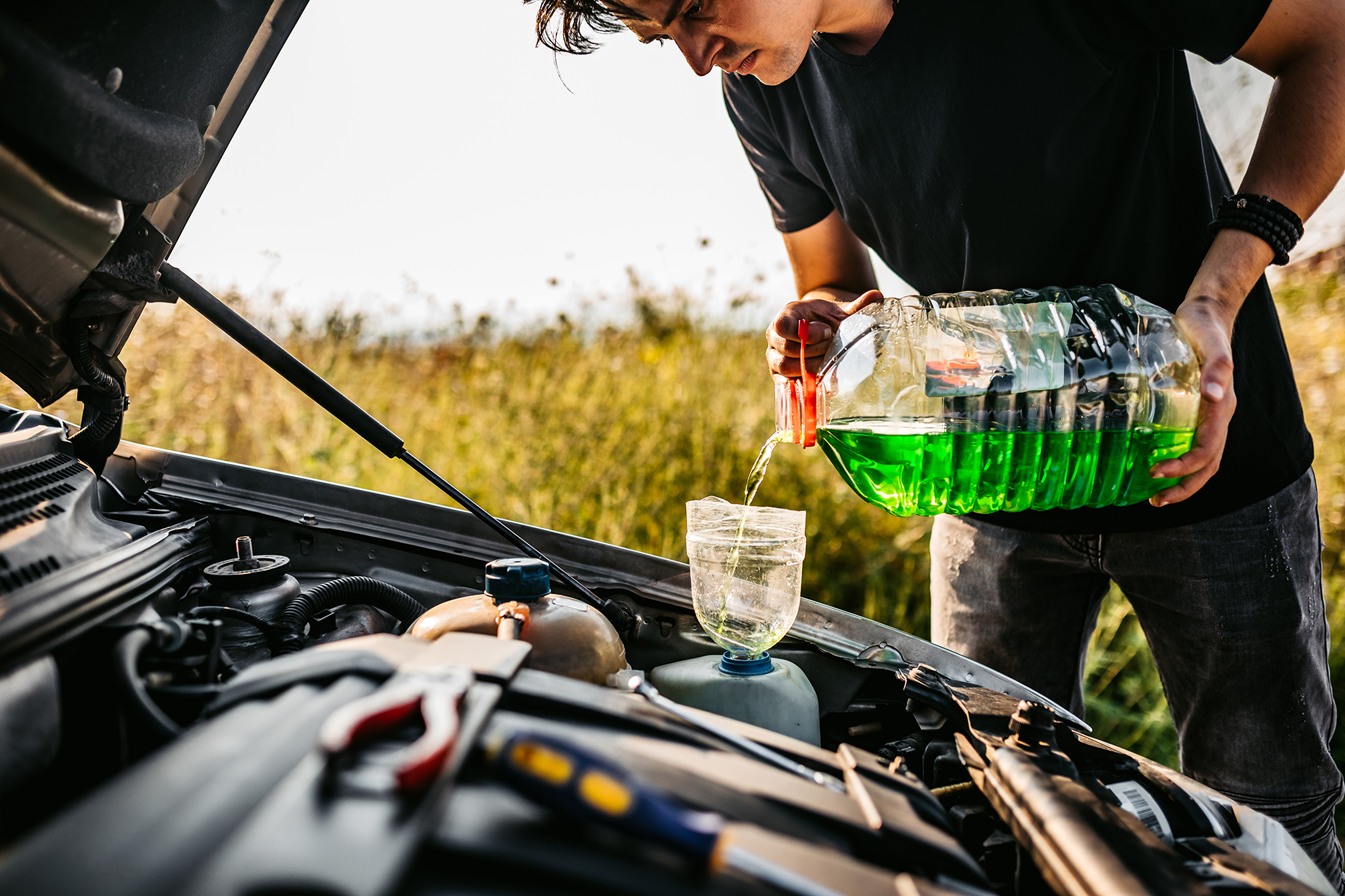 Young Caucasian man Man pouring cleaning car windshield glass liquid or car antifreeze on road.