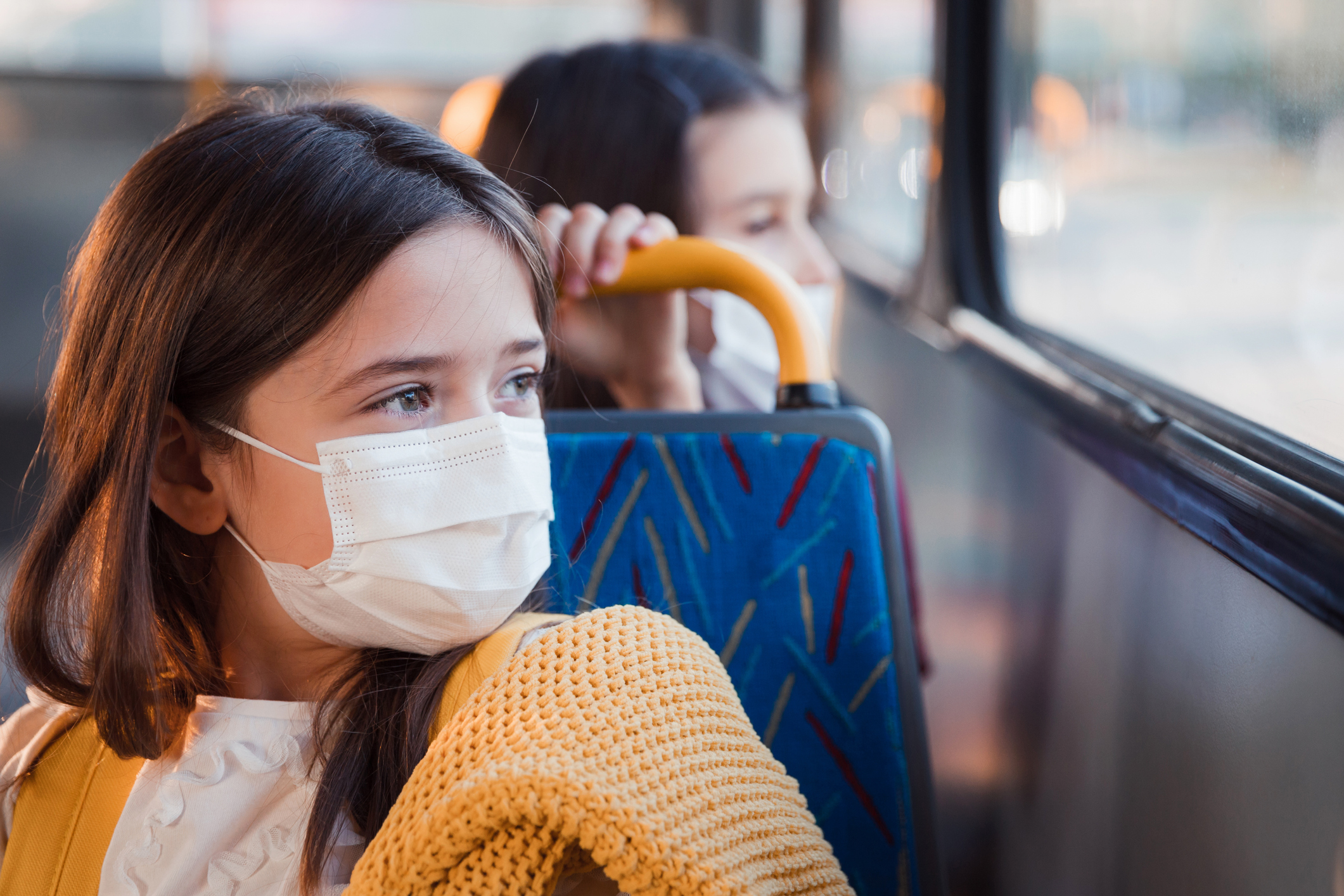 Girl smiling under her protective mask when sitting on a bus