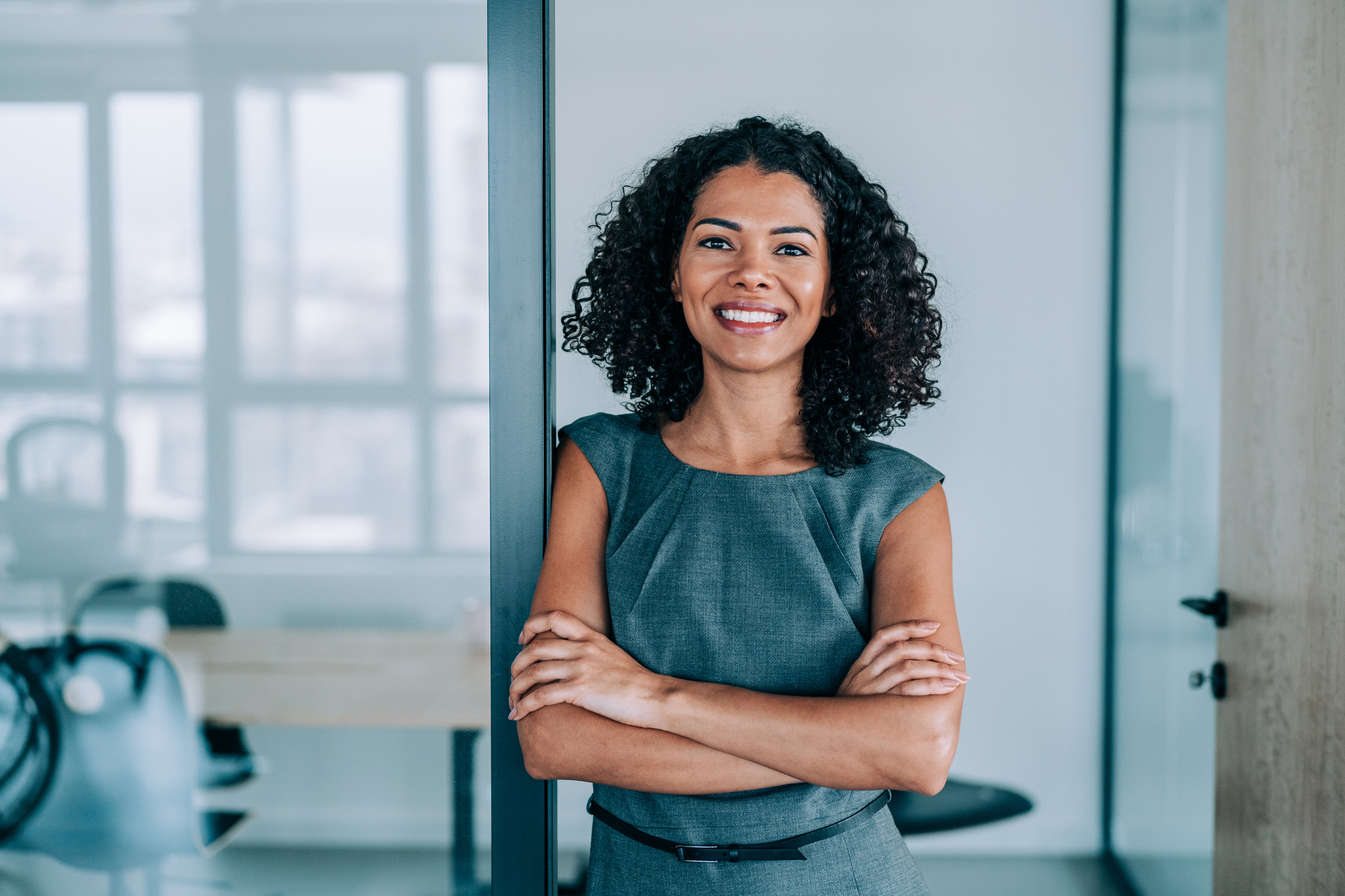 Portrait of beautiful confident smiling african-american businesswoman standing with arms crossed in the office and looking at camera.