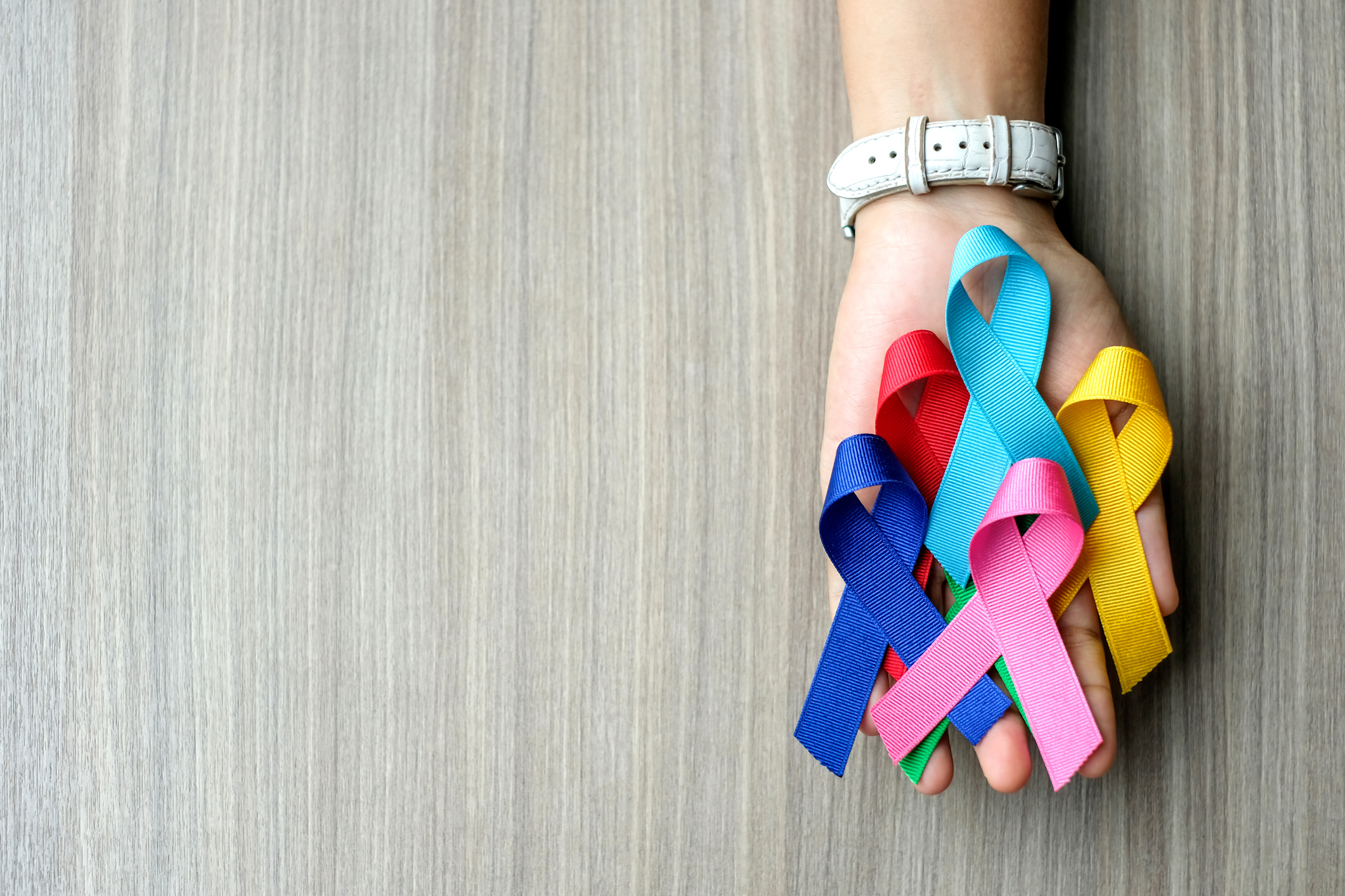 World cancer day (February 4). colorful awareness ribbons; blue, red, green, pink and yellow color on wooden background for supporting people living and illness. Healthcare and medicine concept